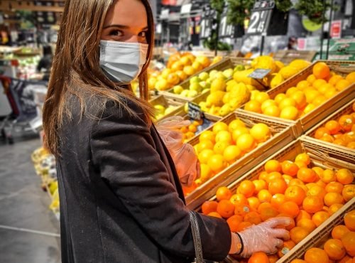 woman in black leather jacket standing in front of orange fruits